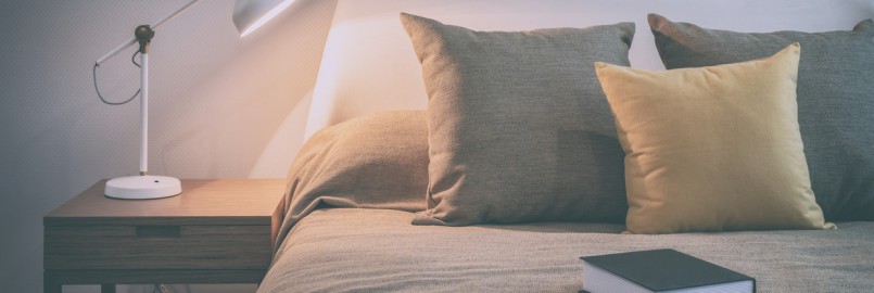 vintage style photo of cozy bedroom interior with book and reading lamp on bedside table